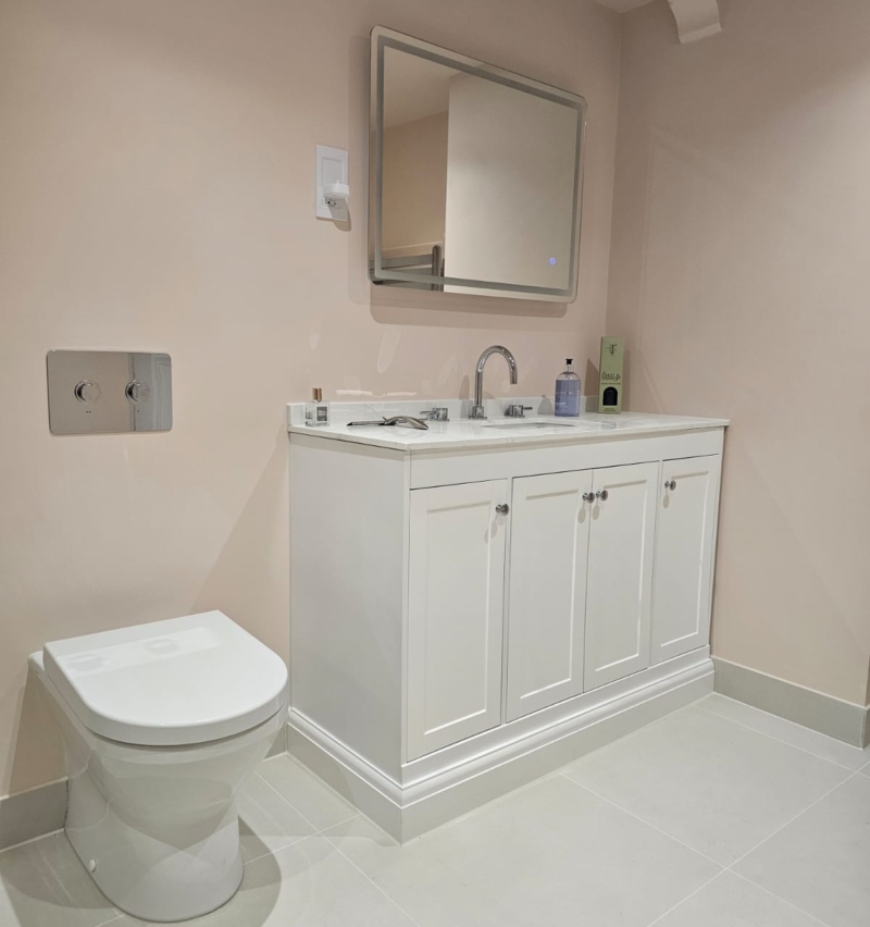Soft pink wet room with traditional toilet and fitted vanity unit