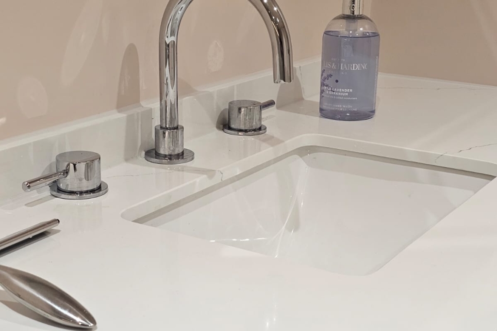 White bathroom basin with traditional chrome taps and soft pink walls