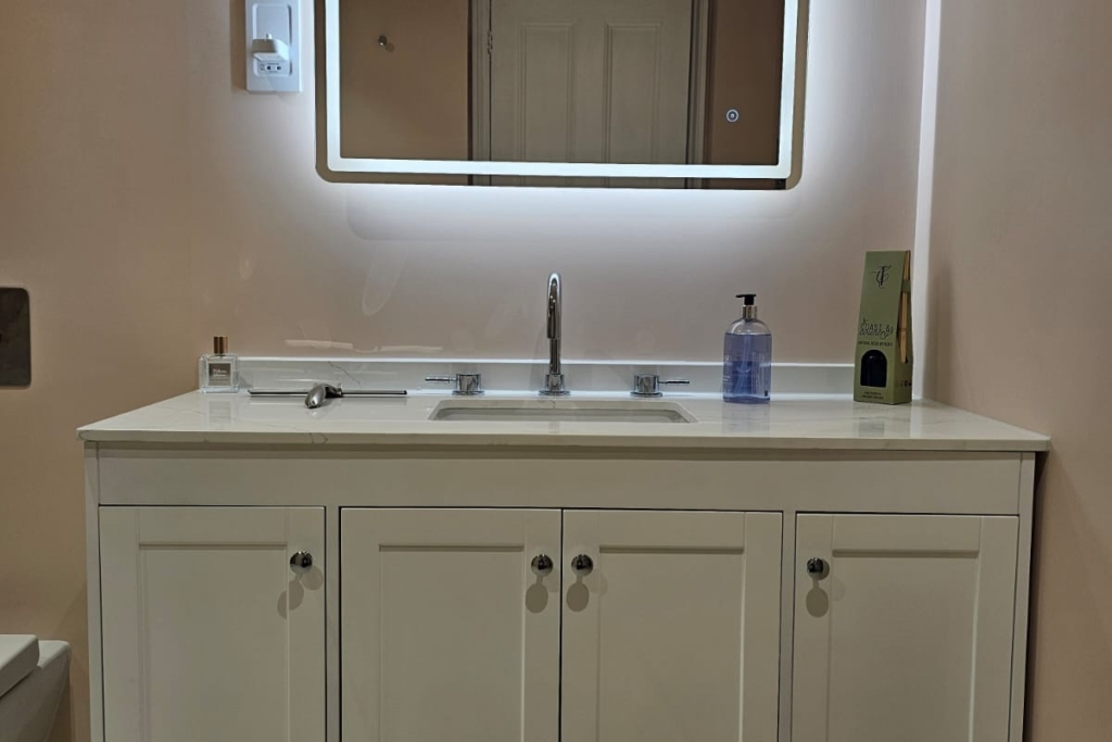 Traditional vanity unit with illuminated mirror in a soft pink wet room
