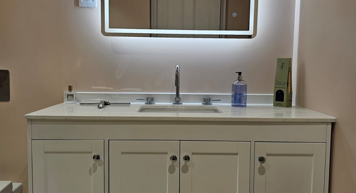 Traditional vanity unit with illuminated mirror in a soft pink wet room