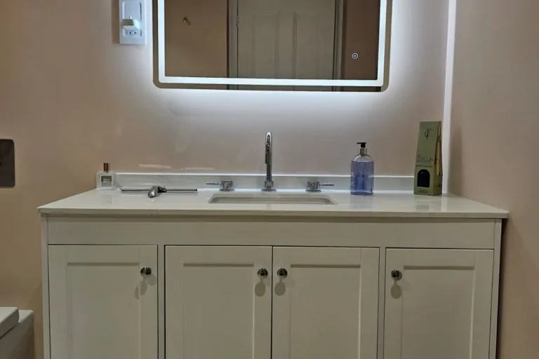 Traditional vanity unit with illuminated mirror in a soft pink wet room