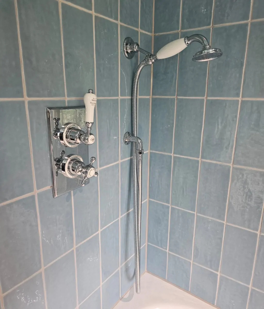 Chrome shower fittings against blue glazed wall tiles