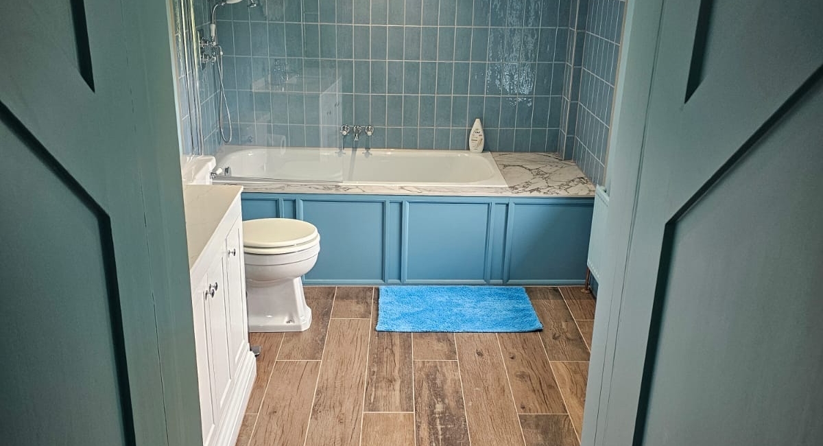Traditional blue bathroom with wood-effect flooring, freestanding basin and built-in storage