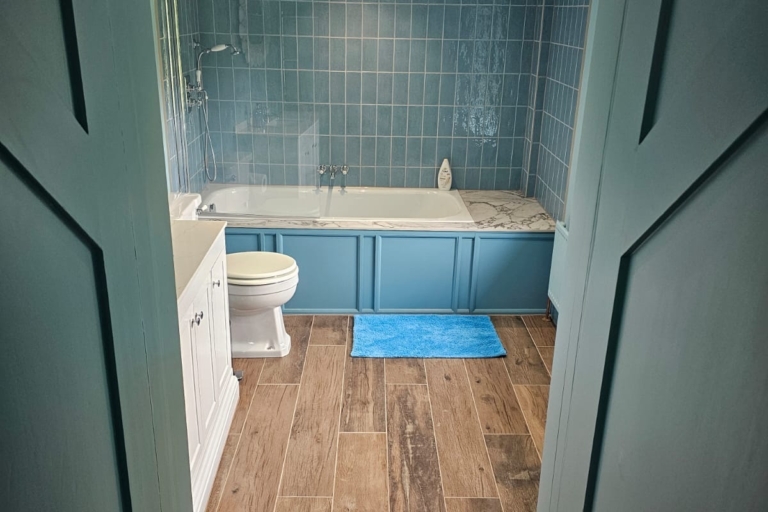 Traditional blue bathroom with wood-effect flooring, freestanding basin and built-in storage