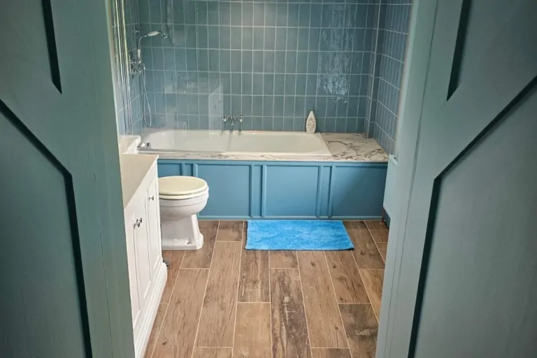 Traditional blue bathroom with wood-effect flooring, freestanding basin and built-in storage