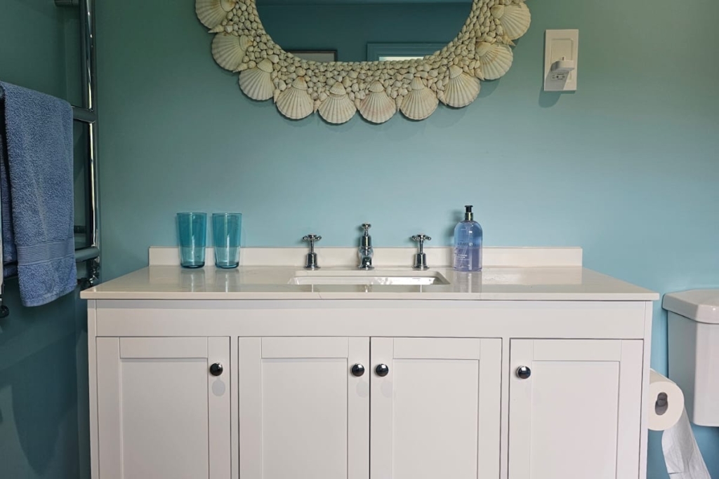 White traditional vanity unit with decorative mirror and blue bathroom walls