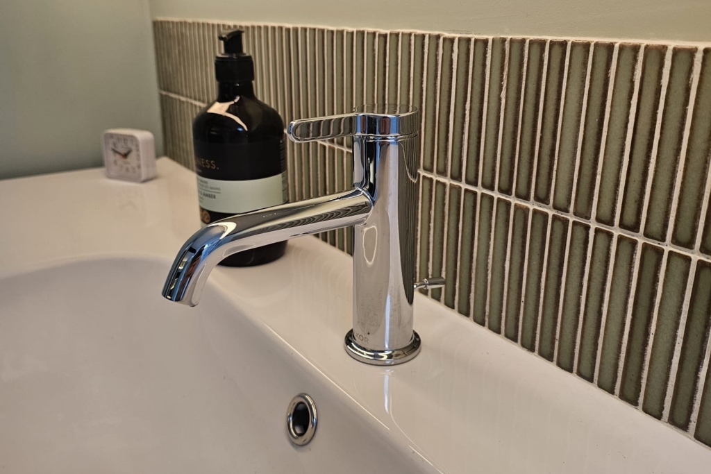 White bathroom basin with chrome tap and textured tiled splashback