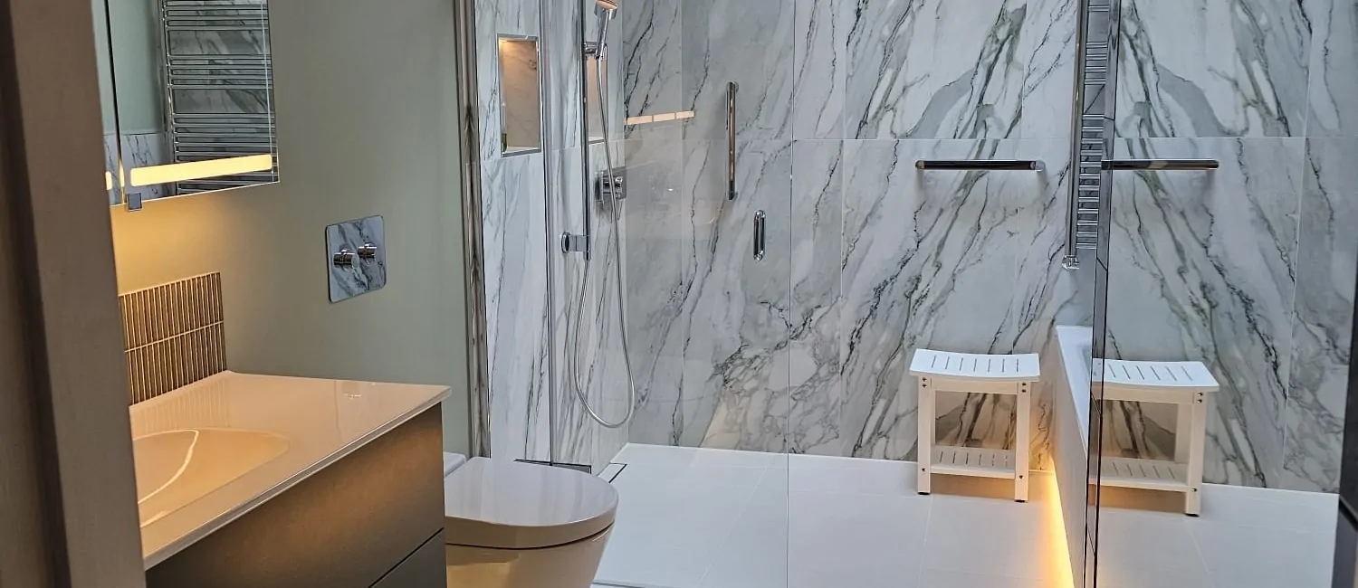 Modern green wet room with marble-effect tiles, wall-hung toilet and illuminated storage