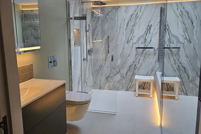 Modern green wet room with marble-effect tiles, wall-hung toilet and illuminated storage
