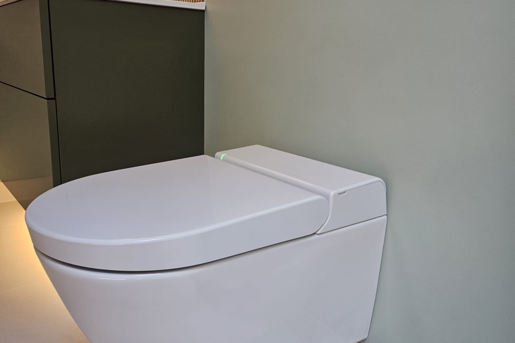 Wall-hung toilet beneath built-in bathroom storage with warm lighting