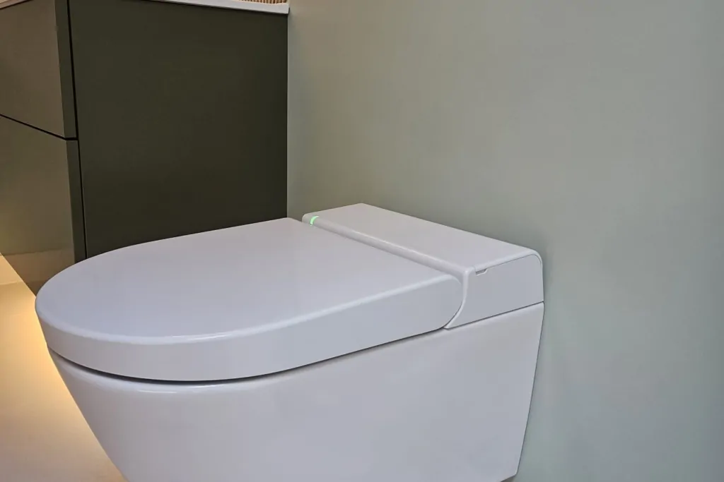 Wall-hung toilet beneath built-in bathroom storage with warm lighting