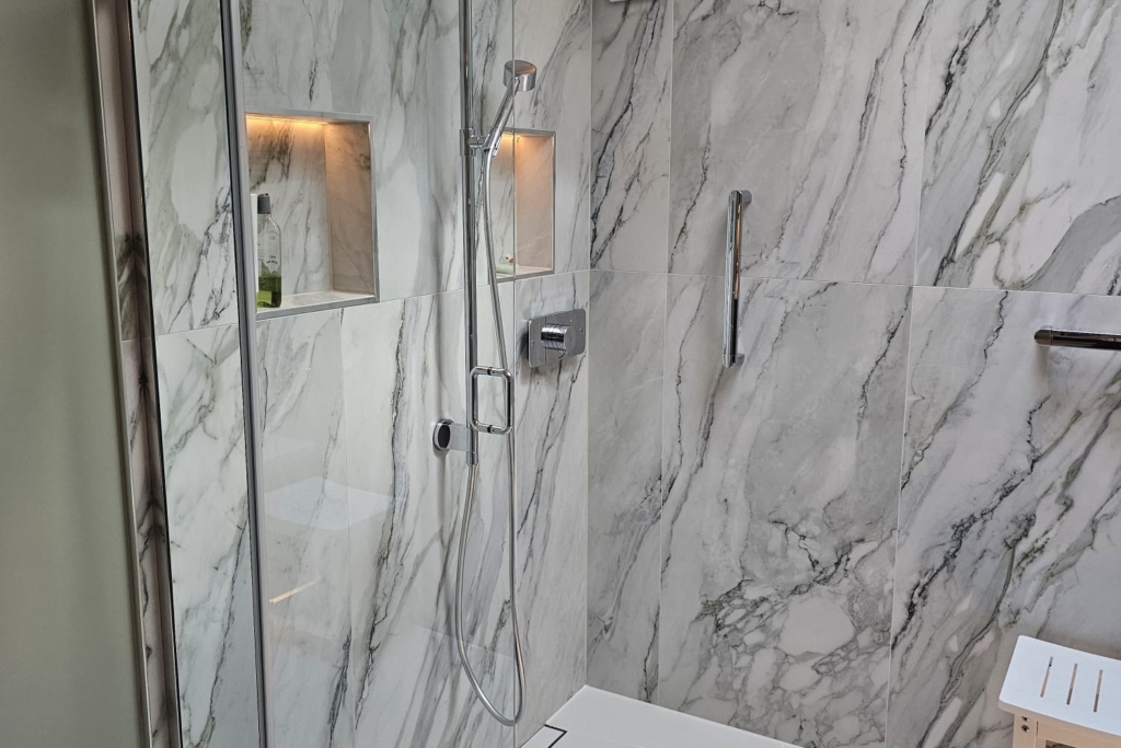 Walk-in shower with glass screen, marble-effect tiles and built-in support features