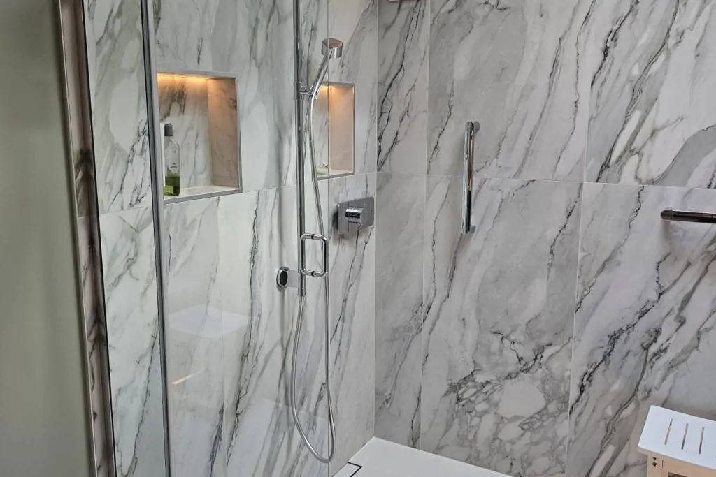 Walk-in shower with glass screen, marble-effect tiles and built-in support features