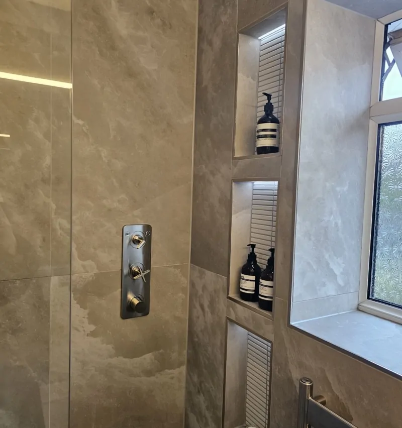 Walk-in shower with recessed storage niches and grey stone-effect wall tiles