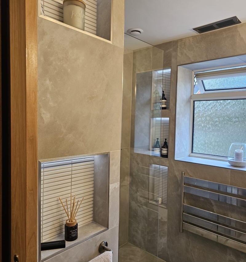 Modern grey bathroom with heated towel rail, recessed shelving and window
