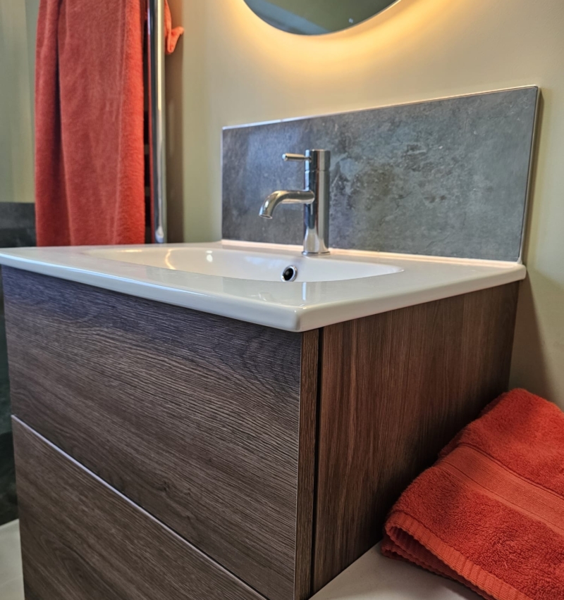 Wall-hung vanity with basin and illuminated mirror in a green wet room
