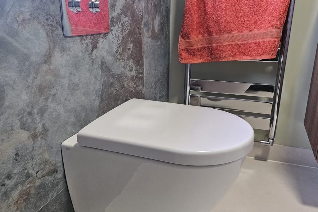 Wall-hung toilet with concealed cistern and grey marble-effect wall tiles