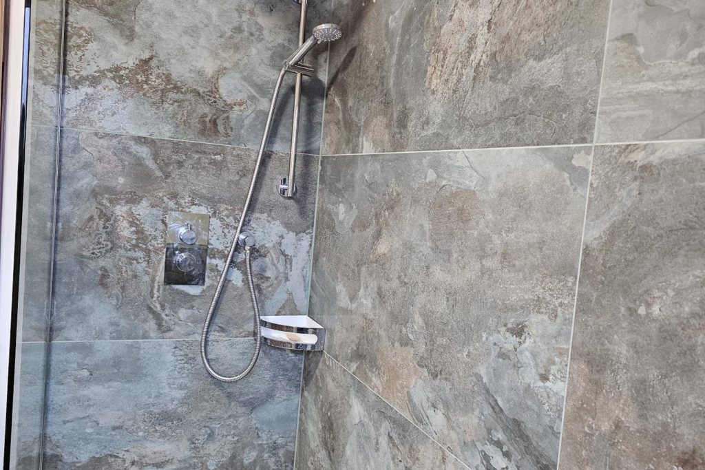 Walk-in wet room shower with grey marble-effect wall and floor tiles
