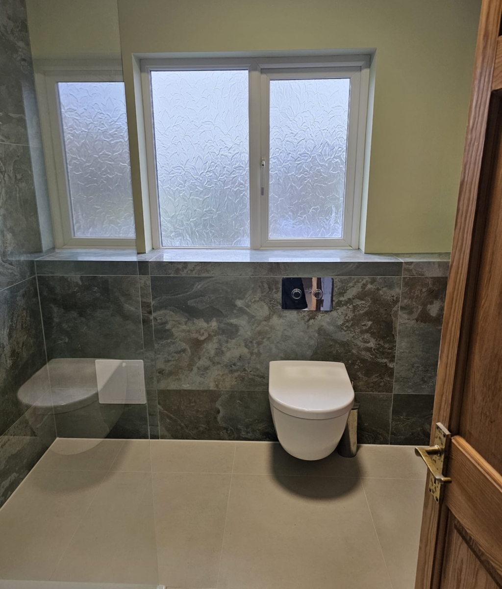 Modern green wet room with walk-in shower, wall-hung toilet and window