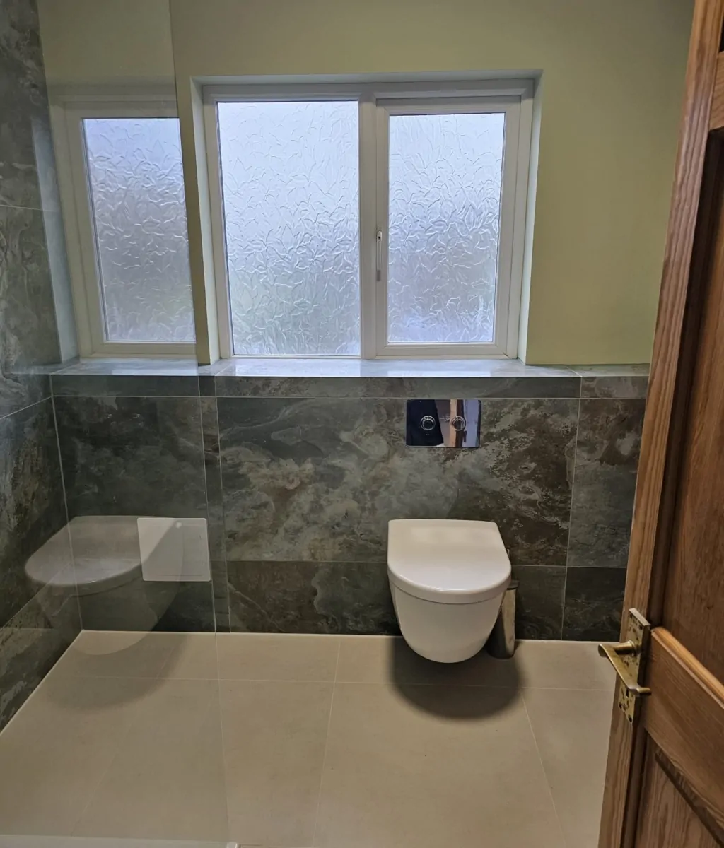 Modern green wet room with walk-in shower, wall-hung toilet and window